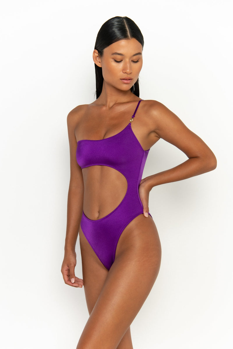 side view elegant woman wearing luxury swimsuit from sommer swim - bonita petunia is a purple one piece one shoulder swimsuit