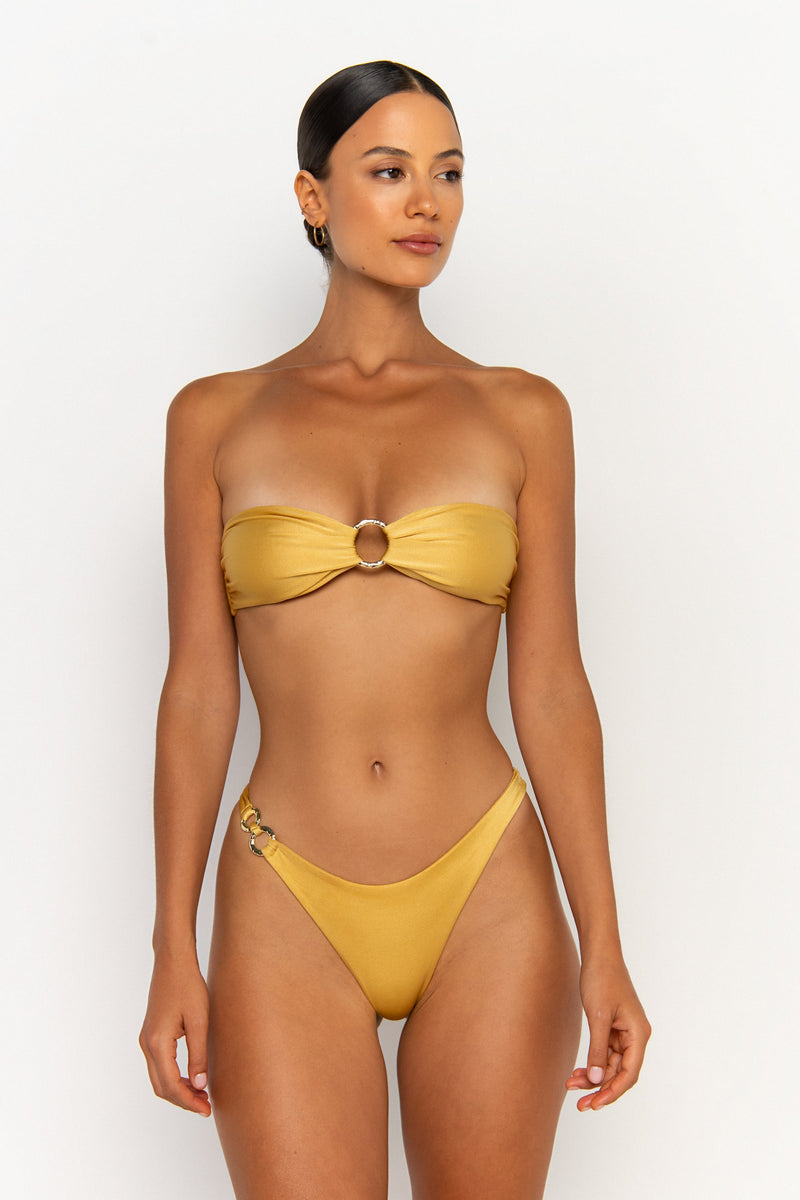 side view elegant woman wearing luxury swimsuit from sommer swim - cece lusso is a golden bikini with a bandeau bikini top