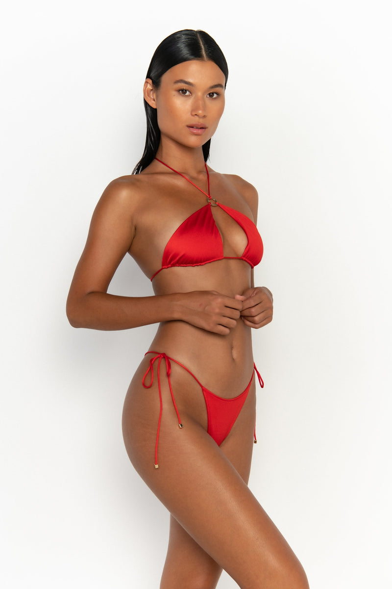side view elegant woman wearing luxury swimsuit from sommer swim - celene siren is a red bikini with a halter style bikini top
