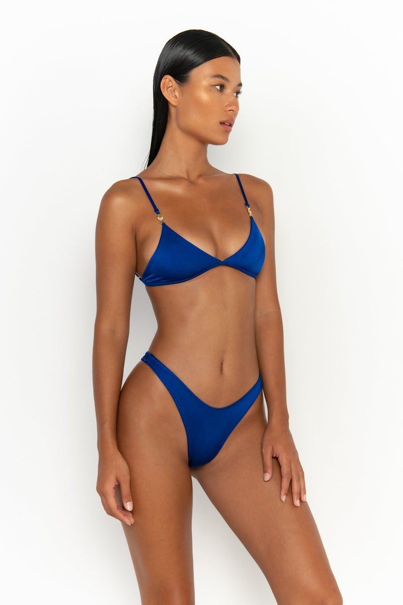 side view elegant woman wearing luxury swimsuit from sommer swim - niam olympus is a royal blue bikini with thong bikini bottom