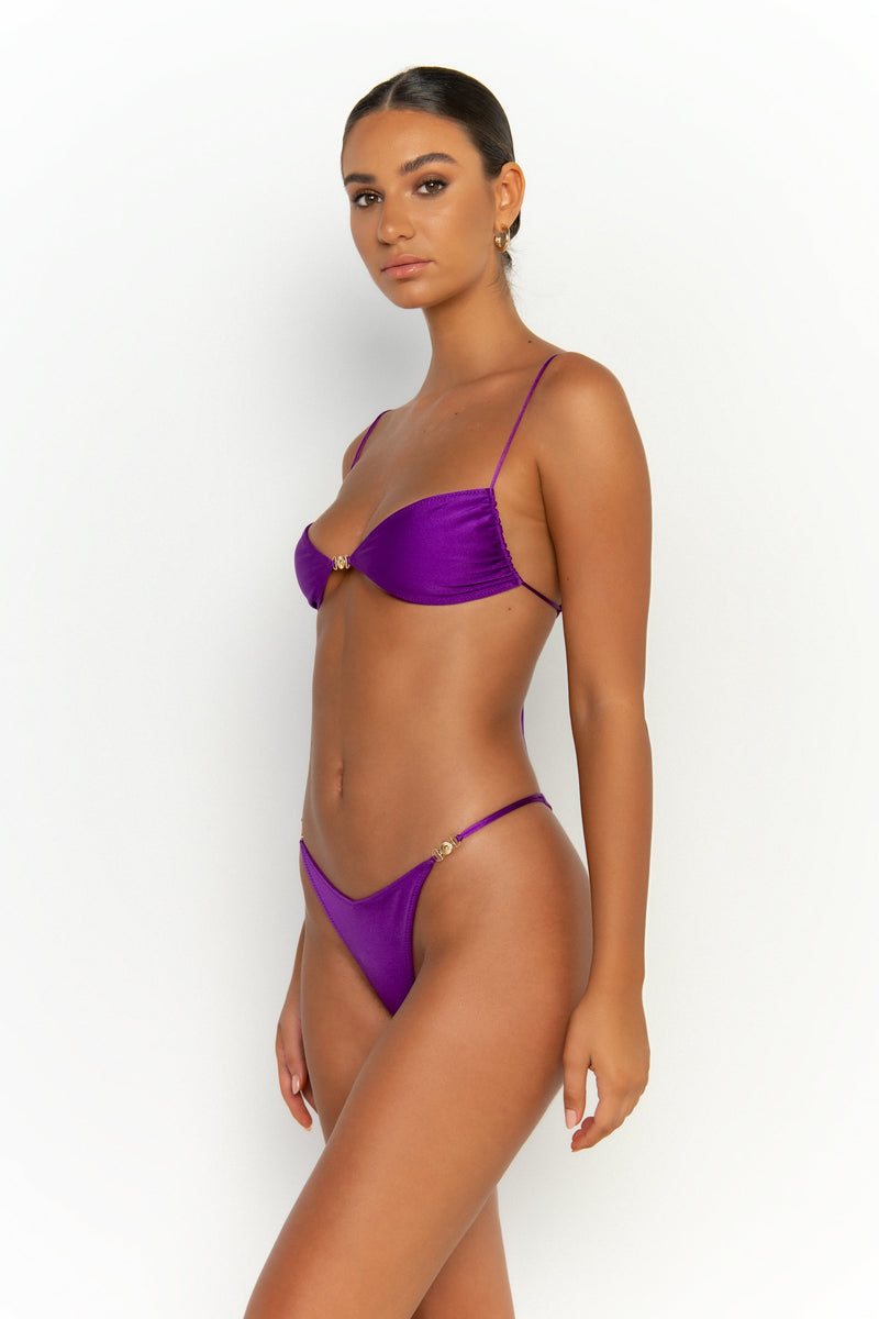 side view elegant woman wearing luxury swimsuit from sommer swim - lia petunia is a purple bikini with brazilian bikini bottom