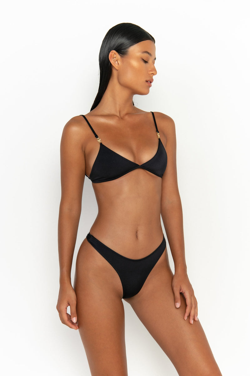 side view elegant woman wearing luxury swimsuit from sommer swim - niam nero is a black bikini with thong bikini bottom
