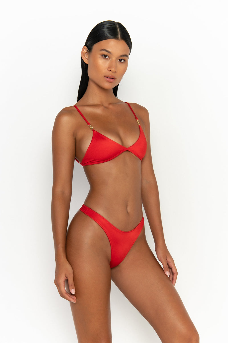 side view elegant woman wearing luxury swimsuit from sommer swim - niam siren is a red bikini with thong bikini bottom