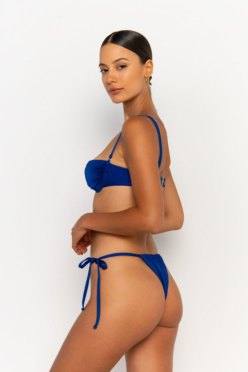 side view elegant woman wearing luxury swimsuit from sommer swim - paloma olympus is a royal blue bikini with tie side bikini bottom