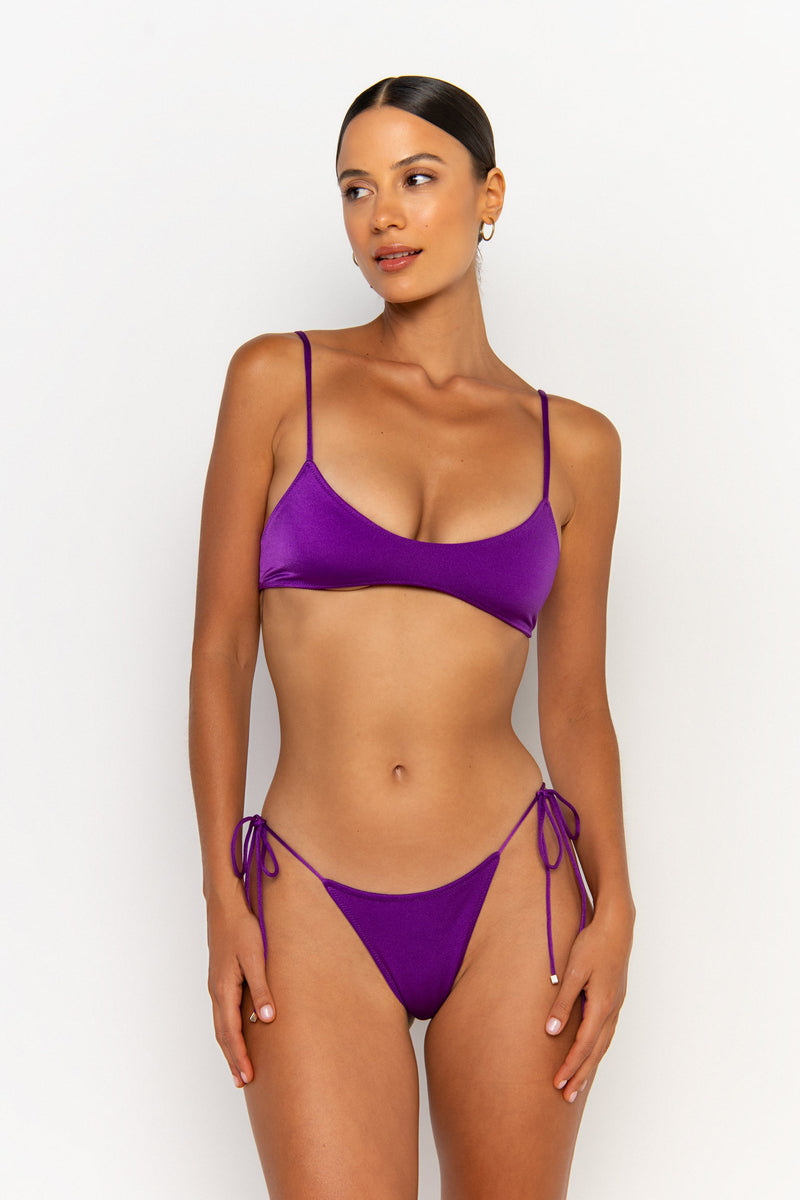 front looking sideways view elegant woman wearing luxury swimsuit from sommer swim - pilar petunia is a purple bikini with bralette bikini top