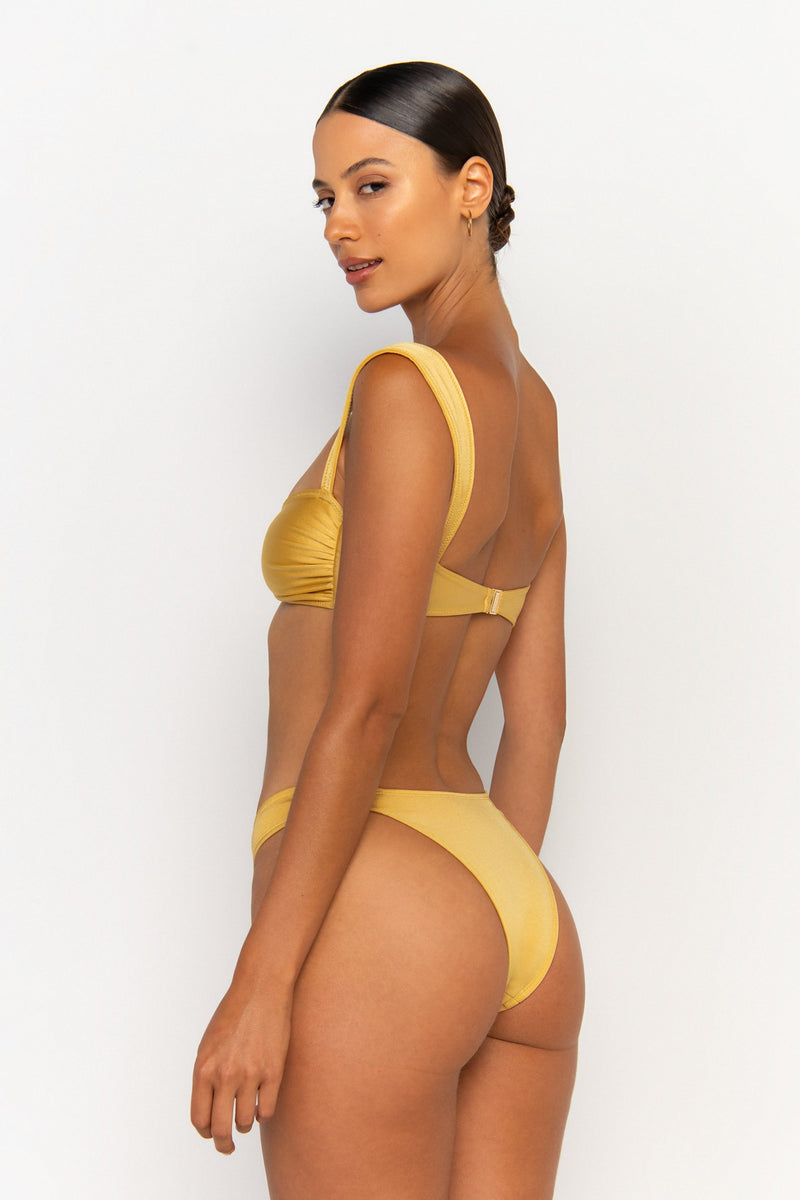 back view elegant woman wearing luxury swimsuit from sommer swim - soriya lusso is a golden bikini with balconette bikini top