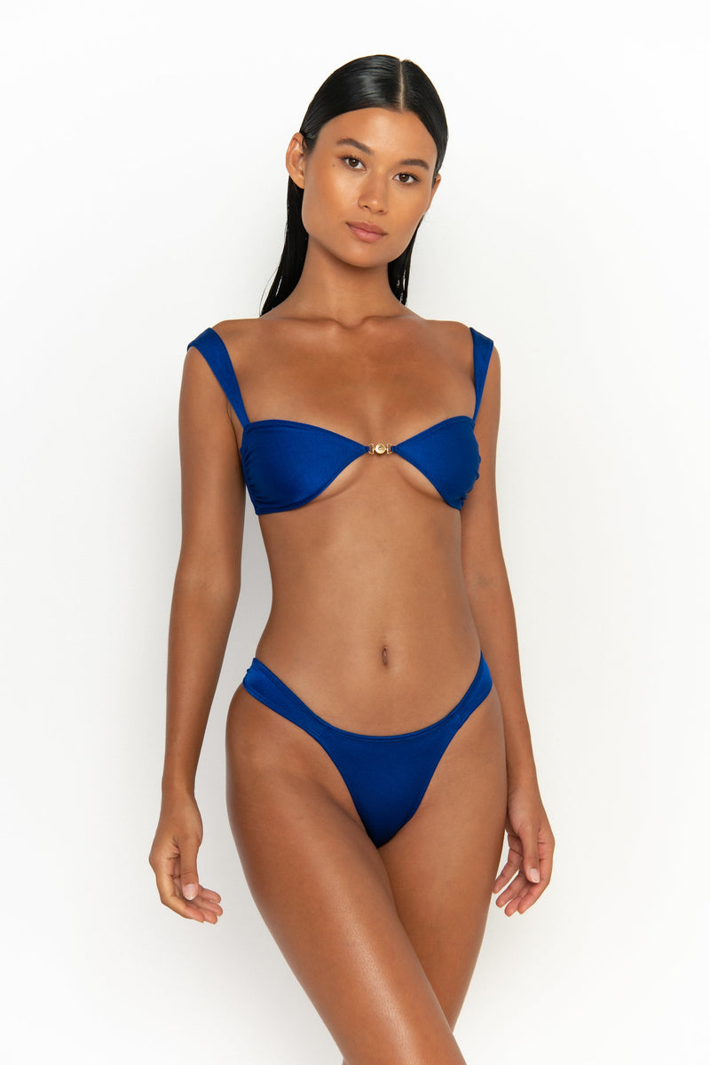 front tilted view elegant woman wearing luxury swimsuit from sommer swim - soriya olympus is a royal blue bikini with balconette bikini top