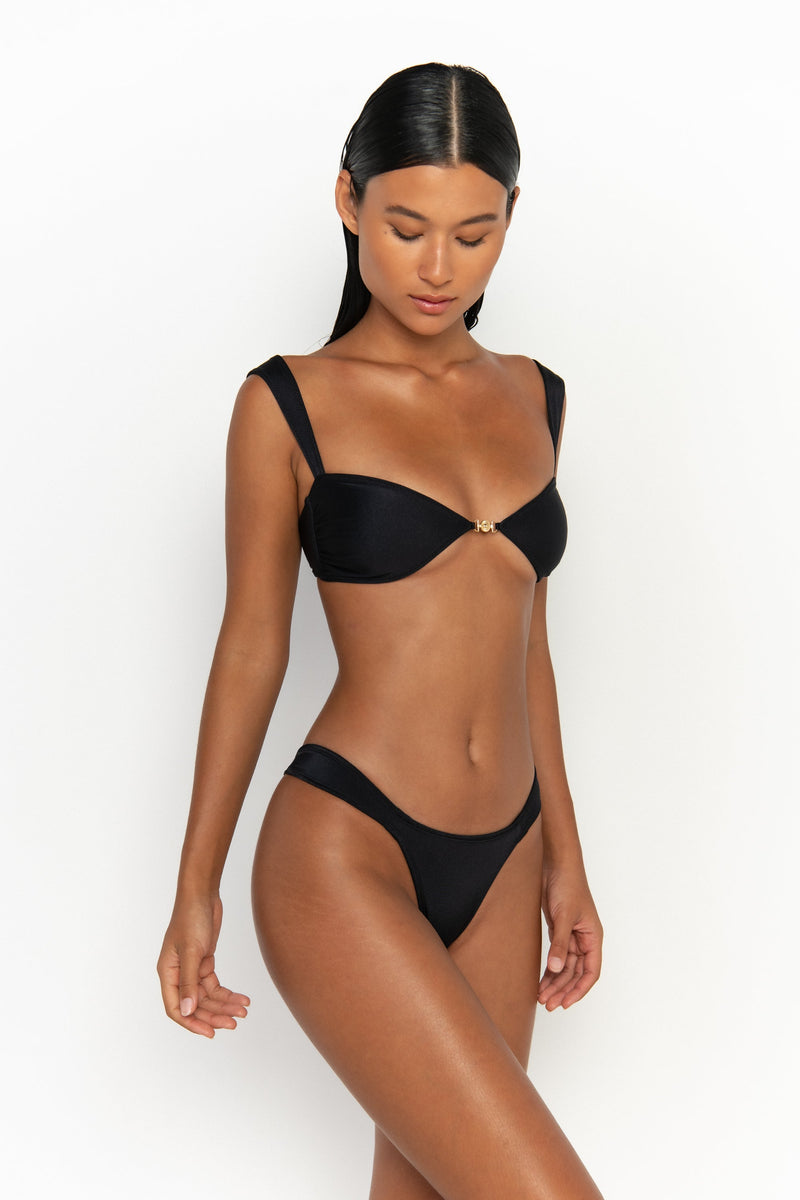 side view elegant woman wearing luxury swimsuit from sommer swim - zita nero is a black bikini with cheeky bikini bottom