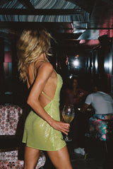 model side view elegant woman wearing luxury resort wear from sommer swim - ibiza chartreuse is a light green sequin mini dress