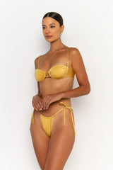side view elegant woman wearing luxury swimsuit from sommer swim - harper lusso is a golden bikini with balconette bikini top
