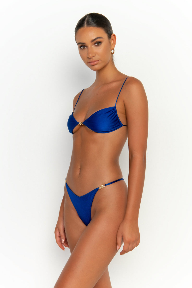 side alternative view elegant woman wearing luxury swimsuit from sommer swim - lia olympus is a royal blue bikini with brazilian bikini bottom