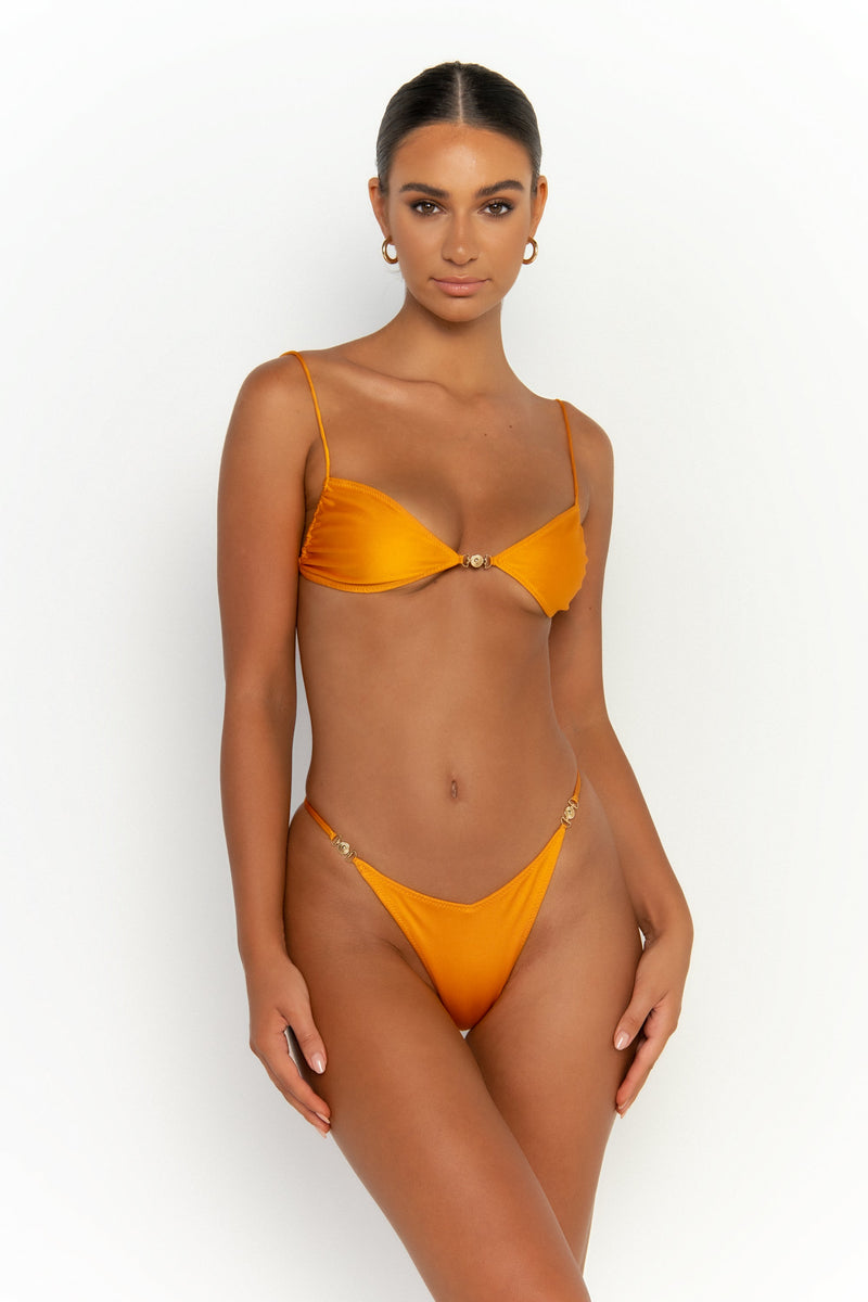 front view elegant woman wearing luxury swimsuit from sommer swim - lia turmeric is a light orange bikini with brazilian bikini bottom